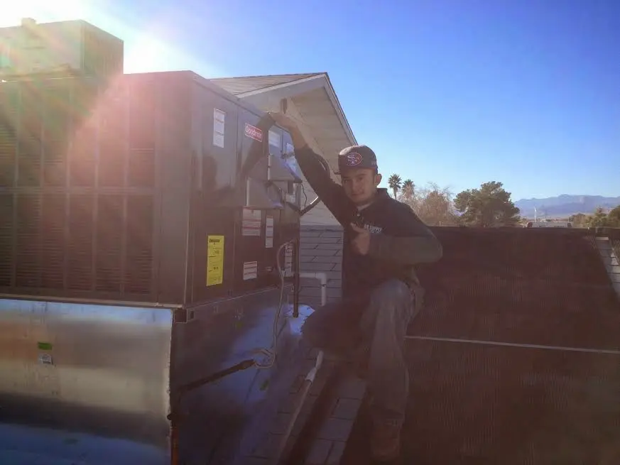 HVAC technician performing Heat Pump Repair on a rooftop unit in Chena Ridge